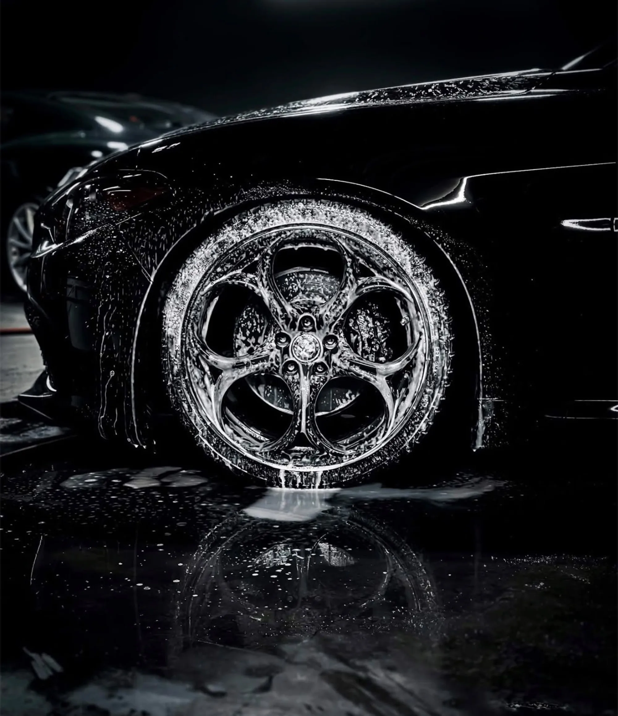 Foam-covered alloy wheel being hand-washed on a black luxury car